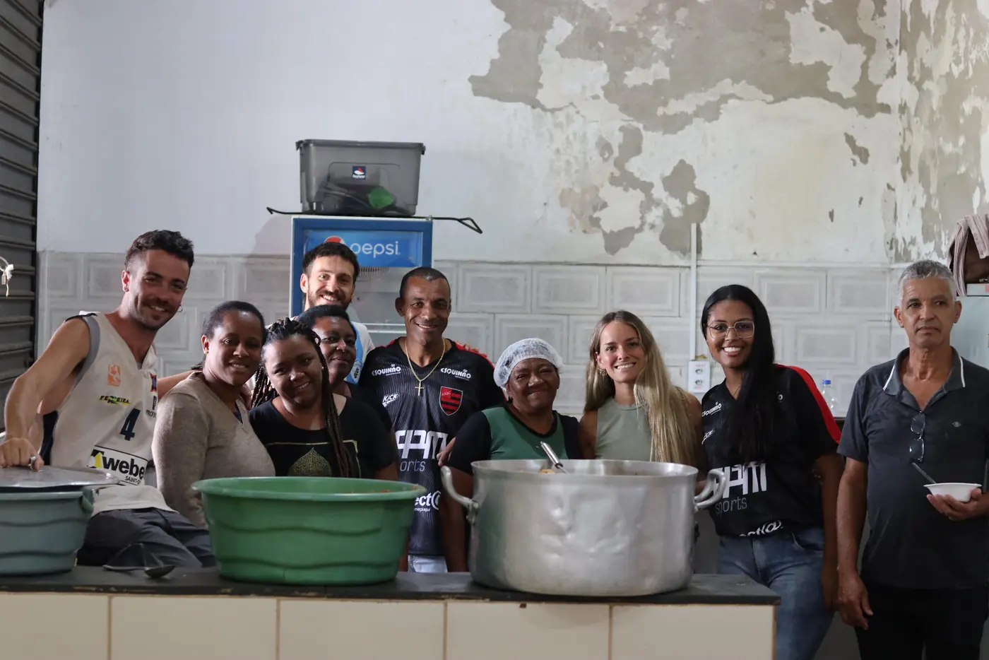 Grupo de personas posando detrás de las ollas en la cocina del club